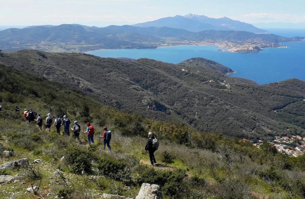 Gruppo di escursionisti sul sentiero del Monte Capannello con vista su Portoferraio e il Monte Capanne