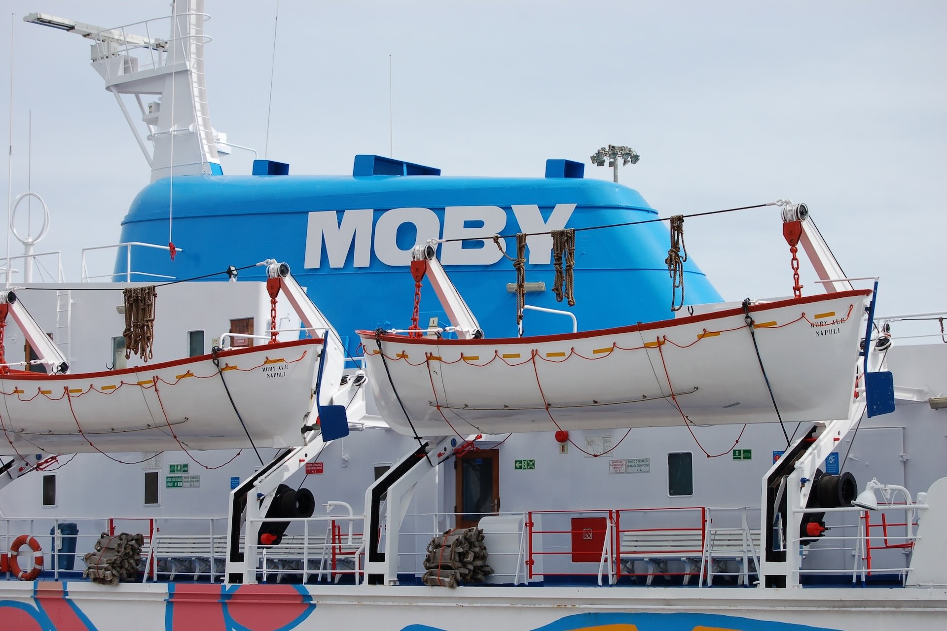Dettaglio del traghetto Moby con scialuppe di salvataggio e fumaiolo azzurro con logo Moby.